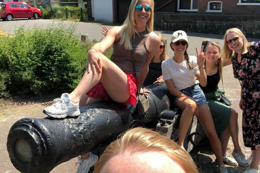 A group of people sitting on a large black pipe in an outdoor setting. 2