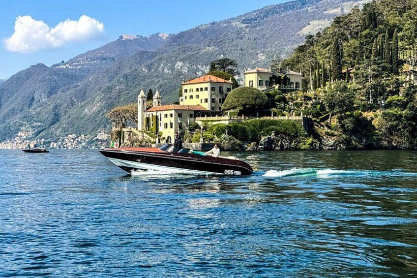 A boat on a lake with a mountain backdrop and a building on the shore. 3