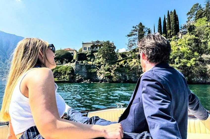 A couple on a boat with a lake and buildings in the background. 2