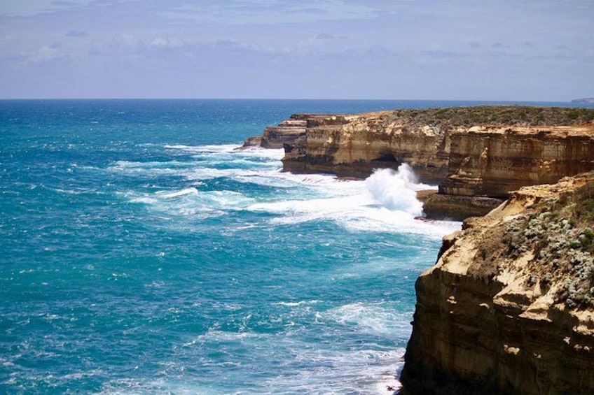 A coastal cliff with waves crashing against it. 2