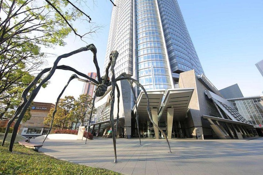 Eine große Spinnenskulptur vor einem modernen Gebäude mit Glasfassade. 1
