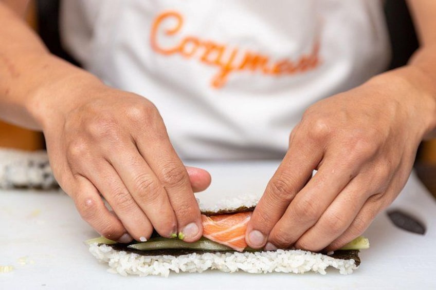 Händer som formar sushi med ris, nori och lax. 2