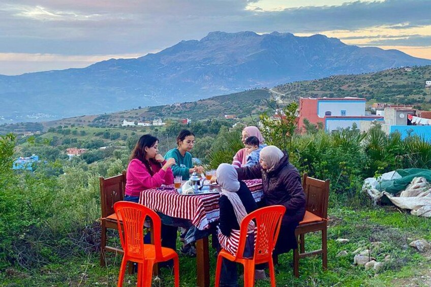 Un groupe de personnes est assis à une table à l'extérieur, avec un paysage montagneux en arrière-plan. 2
