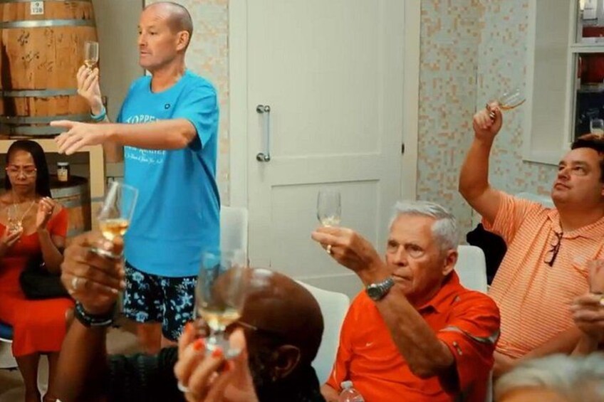 En grupp människor skålar med vinglas i ett rum med ett träfat och tapeter med mönster. 4