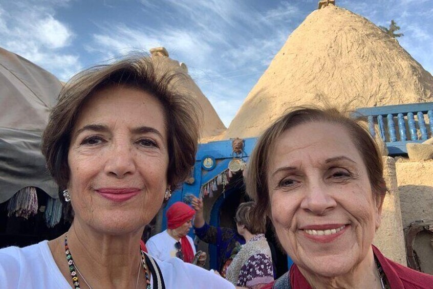 Two people in front of a traditional building with a conical roof. 5