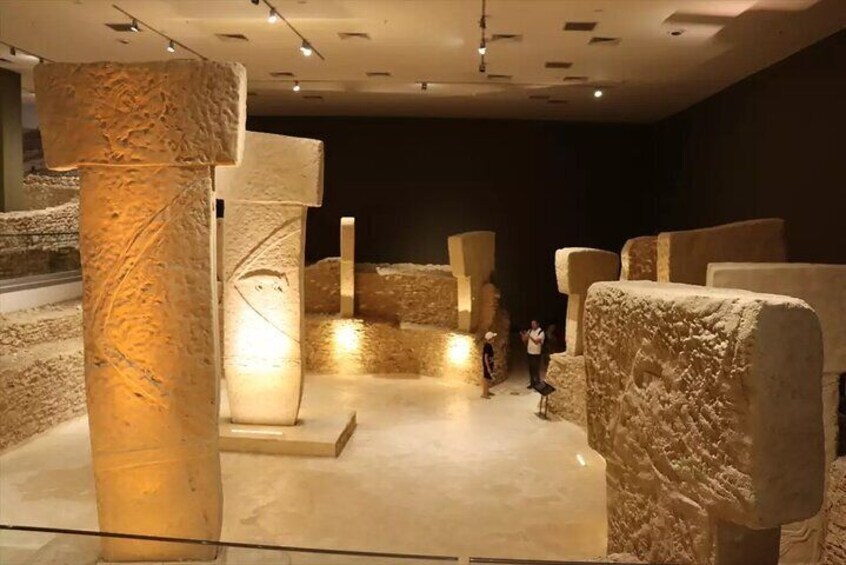 An indoor archaeological exhibit with stone columns and artifacts. 1