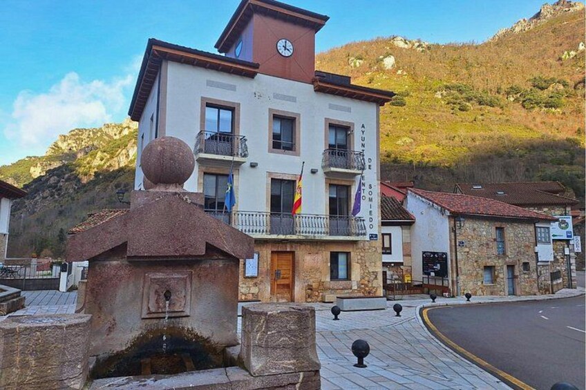 Un edificio con balcones, un reloj y banderas. 2