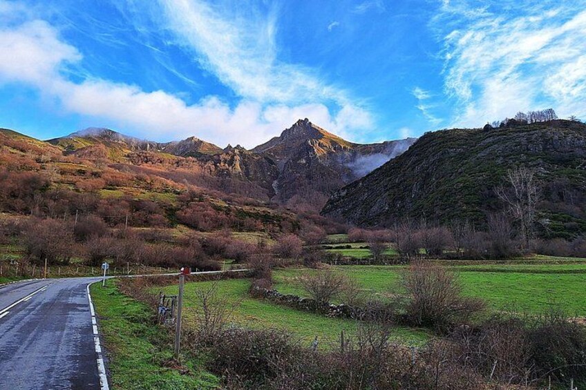 Un paisaje montañoso con una carretera, campos cubiertos de hierba y un cielo despejado. 3