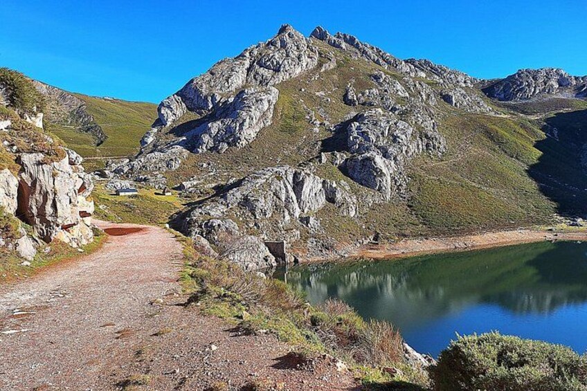 Un sendero de montaña que lleva a un lago rodeado de terreno rocoso. 5