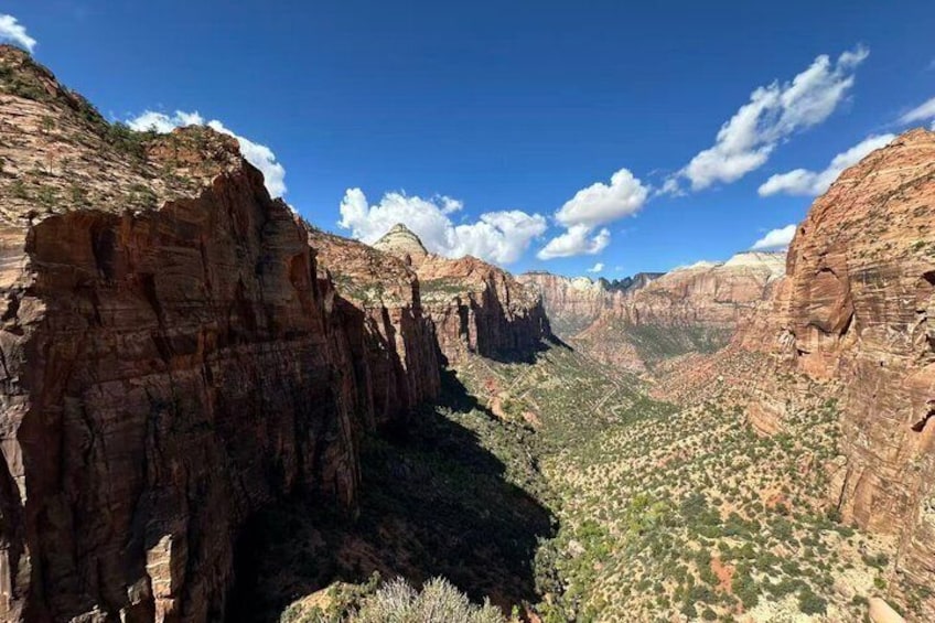 A canyon with layered rock formations and a valley below. 3