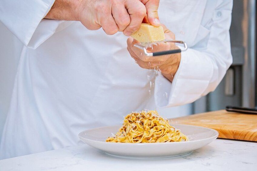 Una persona rallando queso sobre pasta. 5