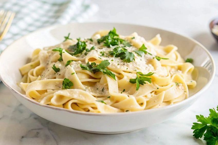 Un plato de pasta con salsa cremosa, adornado con perejil. 4