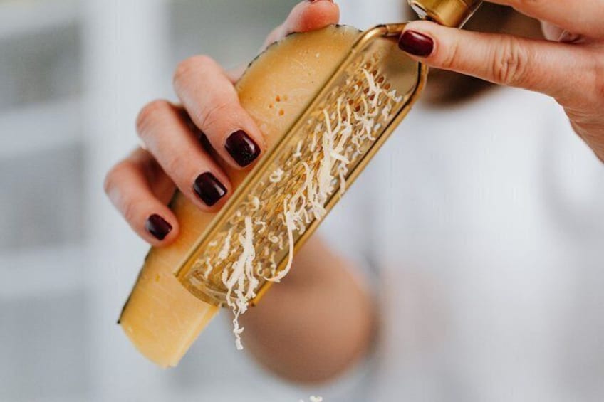 A person using a cheese grater to grate cheese. 5