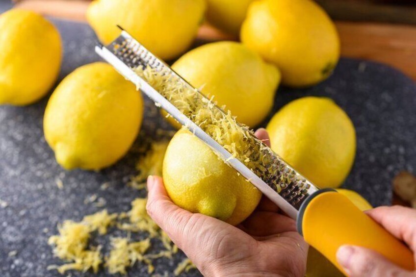 A person grating a lemon with a yellow-handled grater. 2