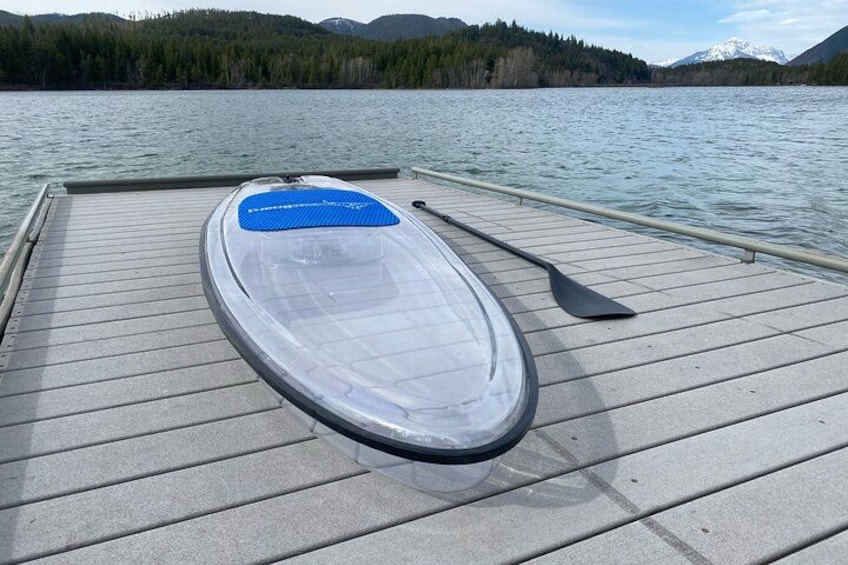 Ein klares Schlauchboot an einem hölzernen Steg am Ufer eines ruhigen Sees mit Bergen im Hintergrund. 4