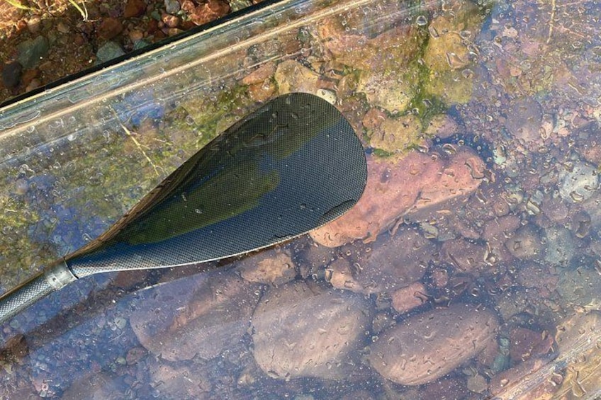 Ein Paddel, das teilweise im Wasser liegt, über einem steinigen Flussbett. 5
