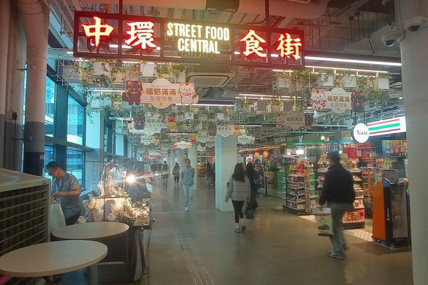 A busy indoor market with food stalls and tables. 2
