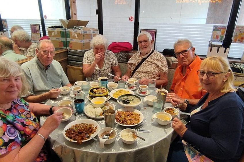 A group of people sitting around a table with various dishes. 5