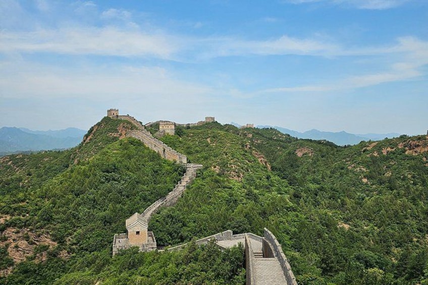 The Great Wall of China winding through lush green hills, with watchtowers and ancient fortifications. 3
