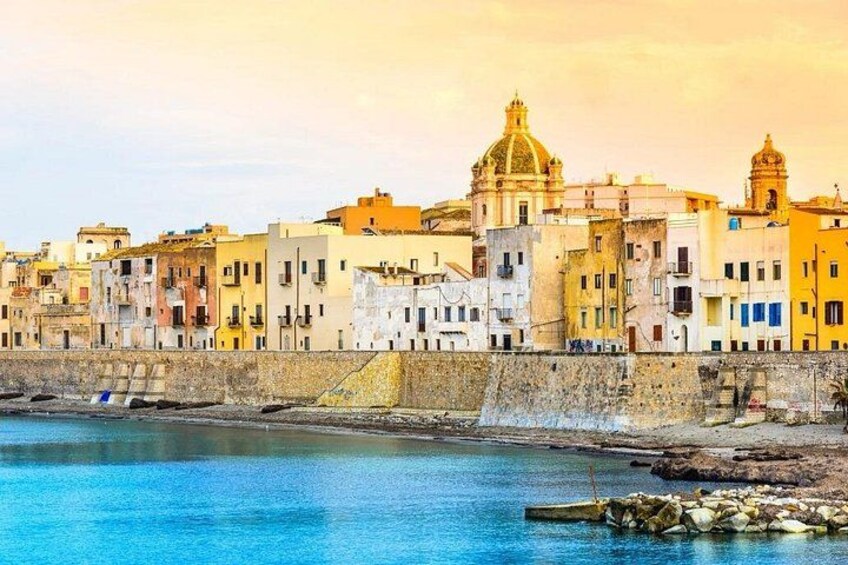 Paesaggio costiero con edifici colorati, una cupola imponente e un mare tranquillo. 3