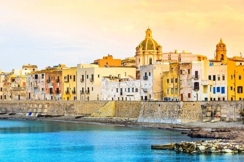 Un paisaje urbano costero con edificios coloridos, una estructura en forma de cúpula destacada y un mar tranquilo. 3