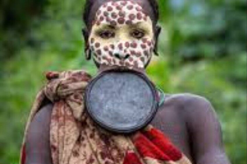 A person with a patterned face and holding a round object. 5
