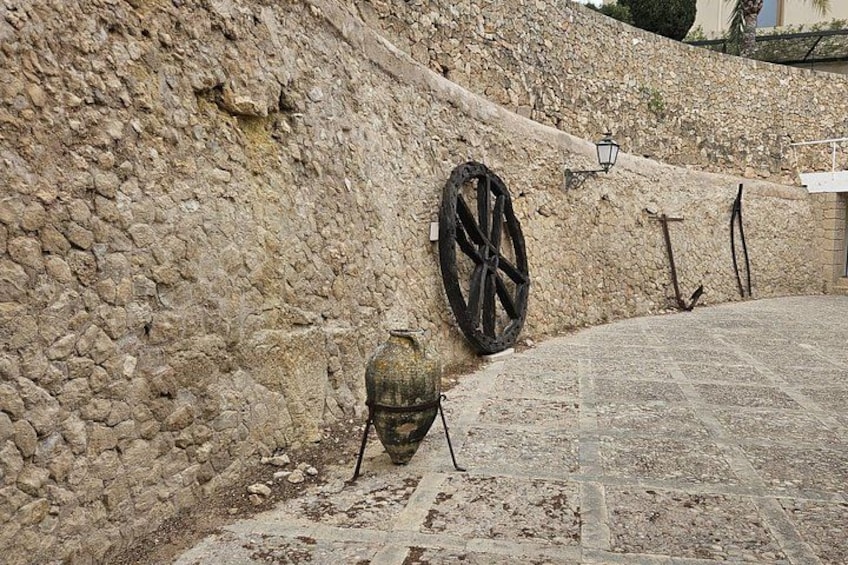 A stone wall with a wheel and a vase. 5