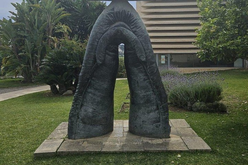 A sculpture of two curved arches in a garden. 3