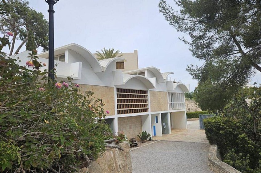 Una casa moderna con tetto curvo, garage e vialetto lastricato. 2