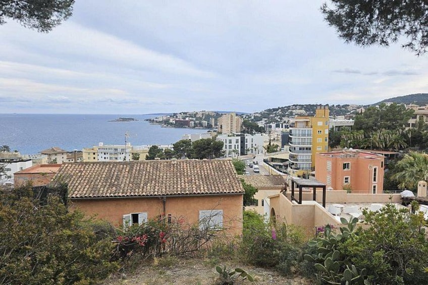 A coastal town with terracotta-roofed buildings, a prominent yellow tower, and a view of the sea. 2