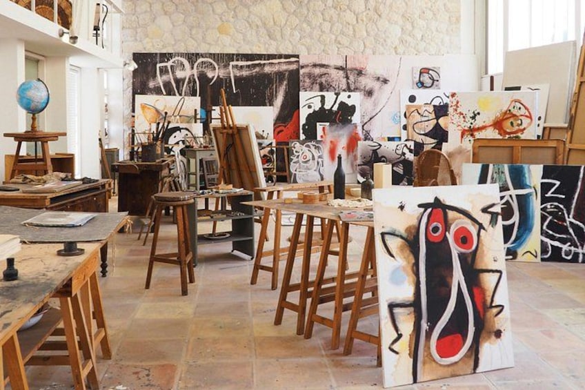 An art studio with various paintings, wooden chairs, and a globe on a shelf. 1