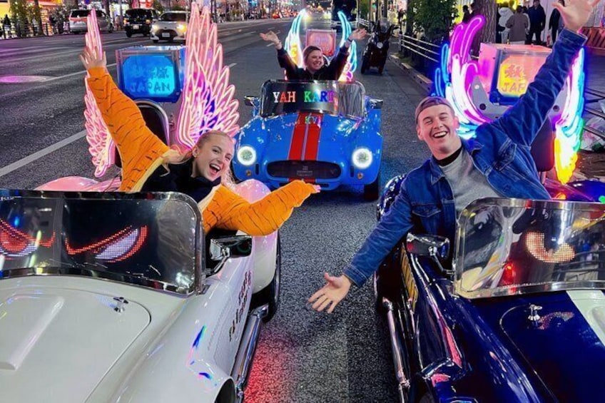 People in colorful, illuminated vehicles on a city street. 4