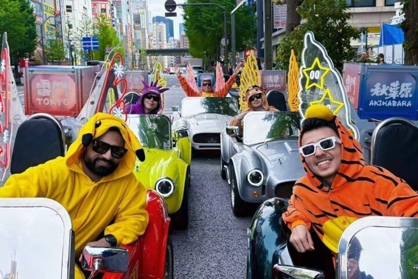 People in colorful costumes driving toy cars on a street. 3