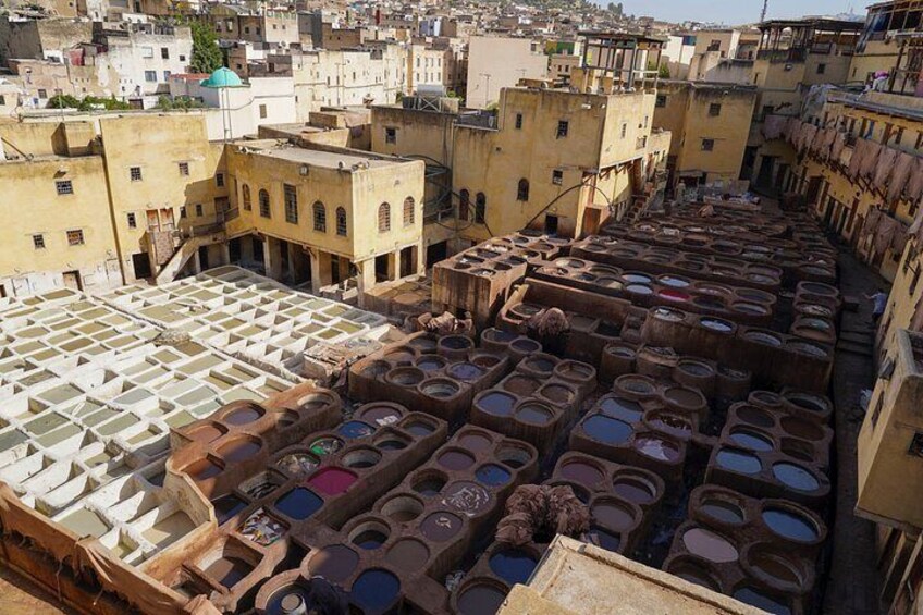 A traditional tanneries area with numerous large vats and wooden racks. 4