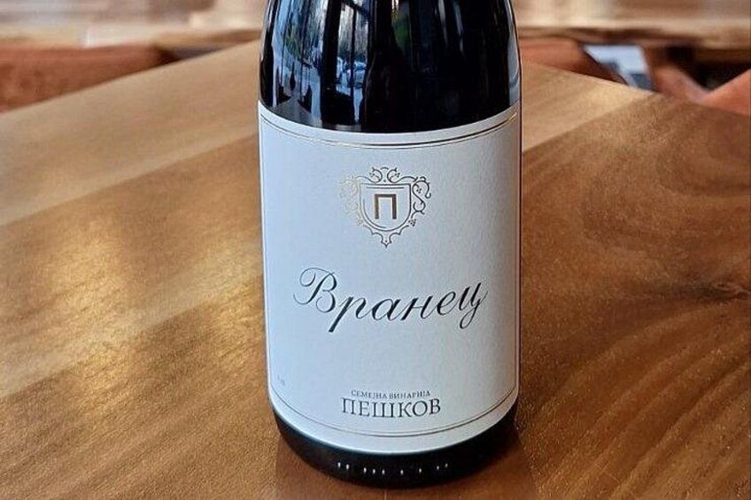 A bottle of wine with a label that includes Cyrillic text and a crest. 3