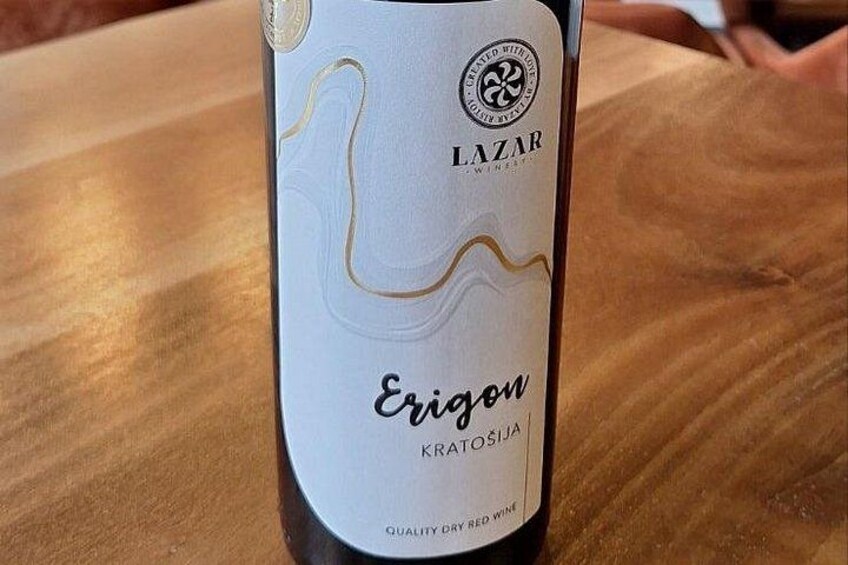 A bottle of Erigon Kratosija wine with a label featuring a wavy line design and the text 'LAZAR QUALITY DRY RED WINE'. 5