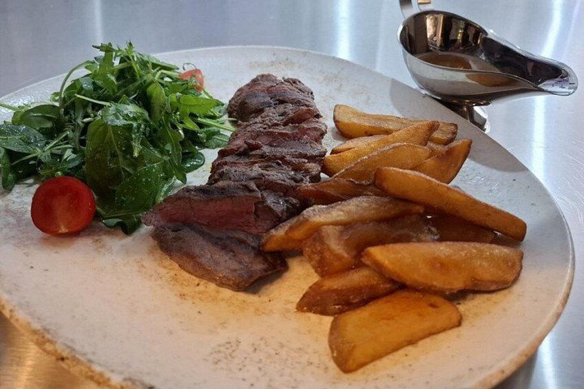 A plate of food with steak, fries, and greens. 1