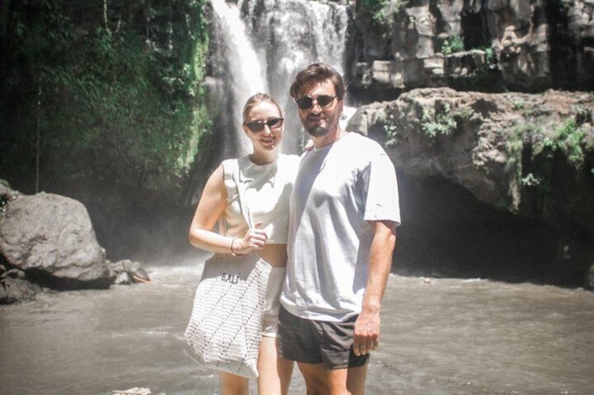 Two people standing by a waterfall in a natural setting. 3