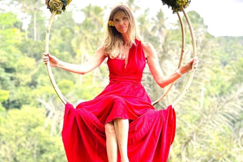 A person in a red dress holding a circular object with greenery. 4
