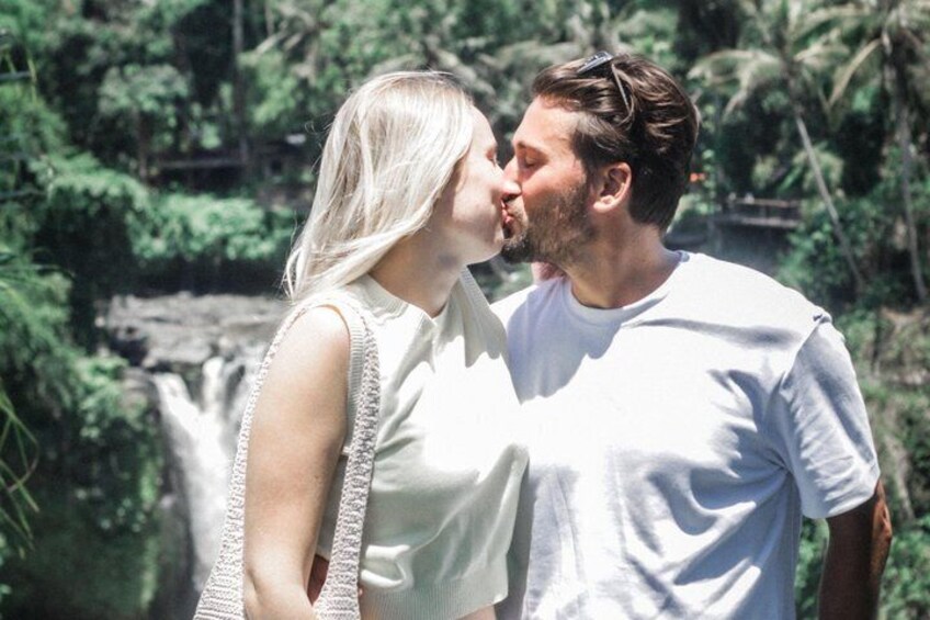 A couple standing close together with a waterfall in the background. 4