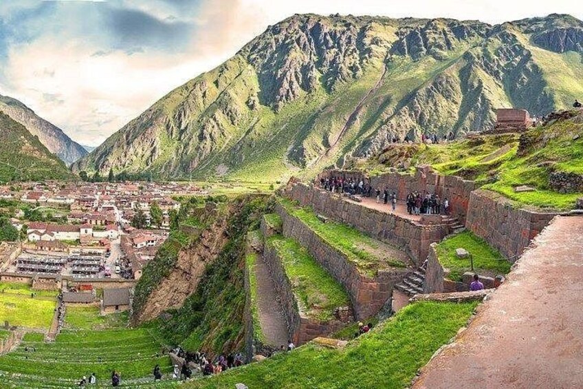 A mountainous landscape with terraced fields, a village, and a stone structure with people. 3