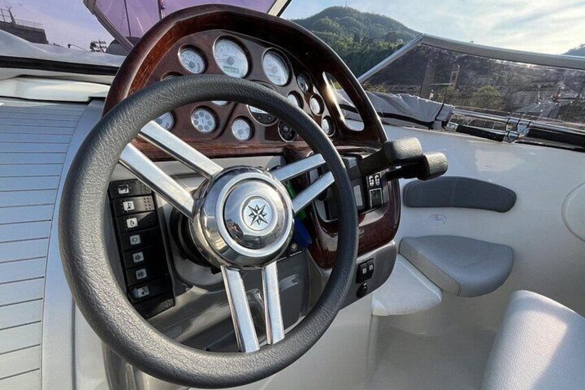 A boat's steering wheel, dashboard, and control panel. 5