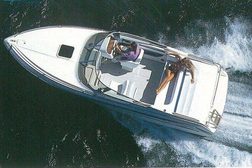 A speedboat with a woman and a man on board, moving through water. 1