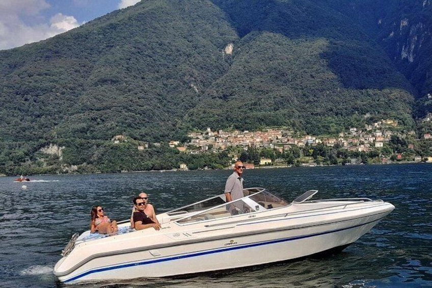 A speedboat on a lake with a mountainous backdrop and a village on the shore. 2