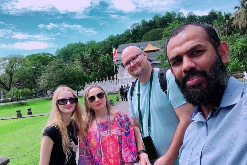 Un groupe de personnes se trouve dans un parc, avec une clôture blanche et de la verdure en arrière-plan. 1