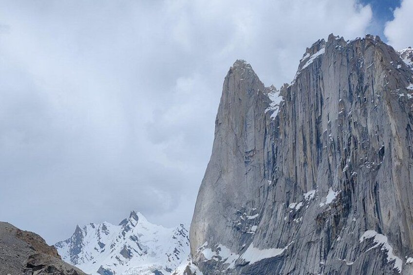 A rugged mountain peak with snow patches, under a cloudy sky. 3