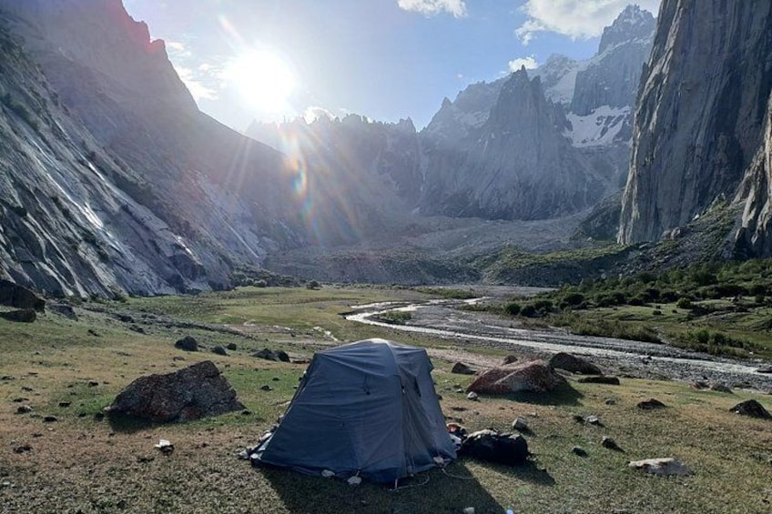 A tent in a mountainous landscape with a river and rocky terrain. 1