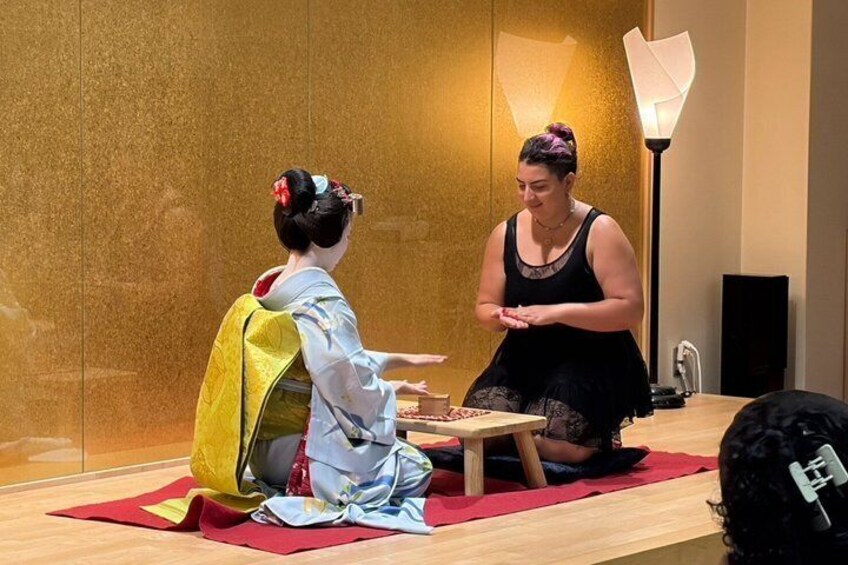 Een persoon in traditionele Japanse kledij zit aan een tafel met een andere persoon. 4