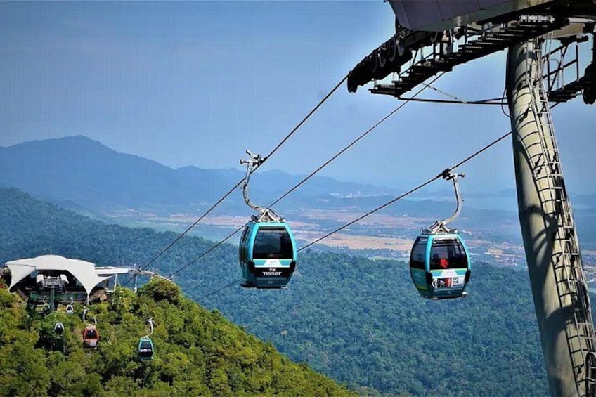 A cable car system with cabins suspended by cables, a mountainous landscape, and a clear sky. 4
