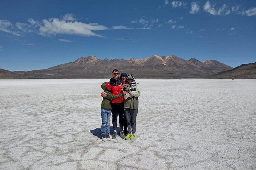 A group of people standing on a salt flat with mountains in the background. 4